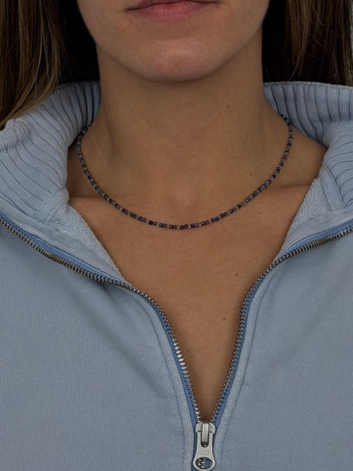 Person wearing a light blue zip-up hoodie with Goldstone & Pebble's custom-light birthstone necklace. 2.5mm beaded birthstone family necklace made with natural gemstones.