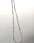 Goldstone & Pebble 3mm natural rough diamond beaded necklace suspended in front of a blank wall. April birthstone. 